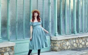 Photographie de Louise Ebel en robe devant un bâtiment vert