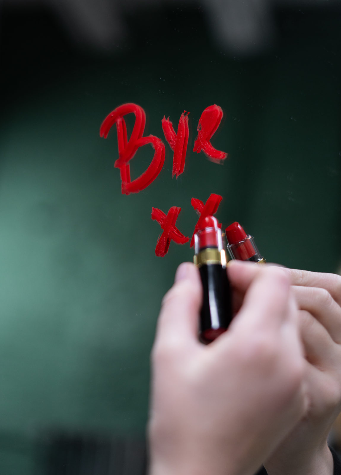 "Bye" écrit au rouge à lèvres rouge sur un miroir. 