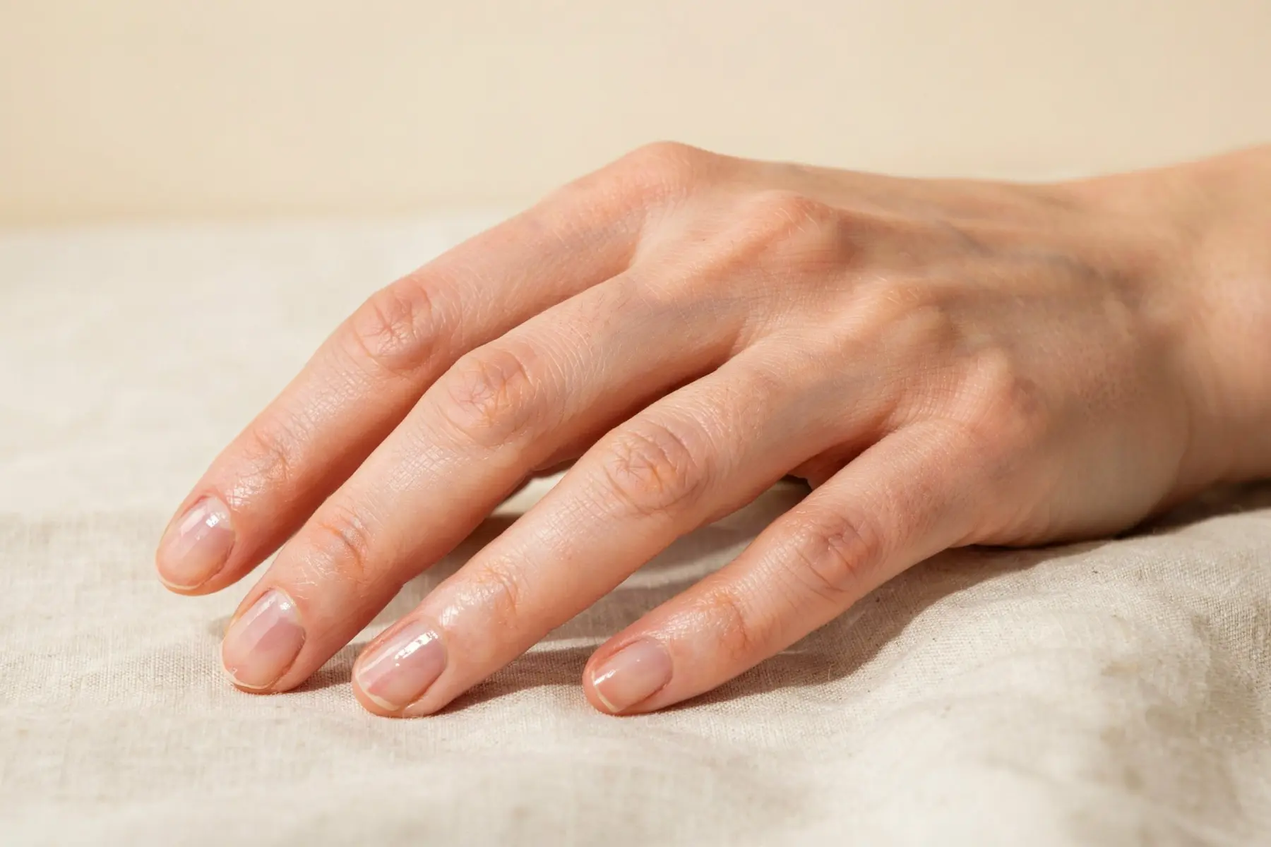 Faux ongles : comment choisir ceux qui tiennent sans abîmer vos ongles naturels 1 Main féminine après 45 ans avec ongles courts naturels et bien hydratés, soin beauté quotidien