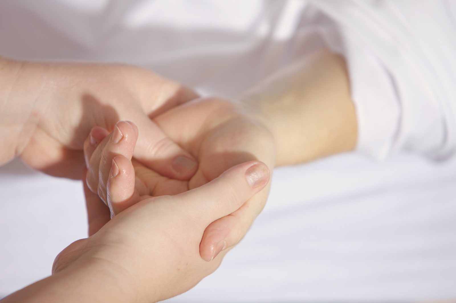 Massage énergétique Reiki réalisé sur une main pour détendre le corps et retrouver le bien-être. Le maître de Reiki exerce une pression avec son pouce dans la paume de la main du consultant.