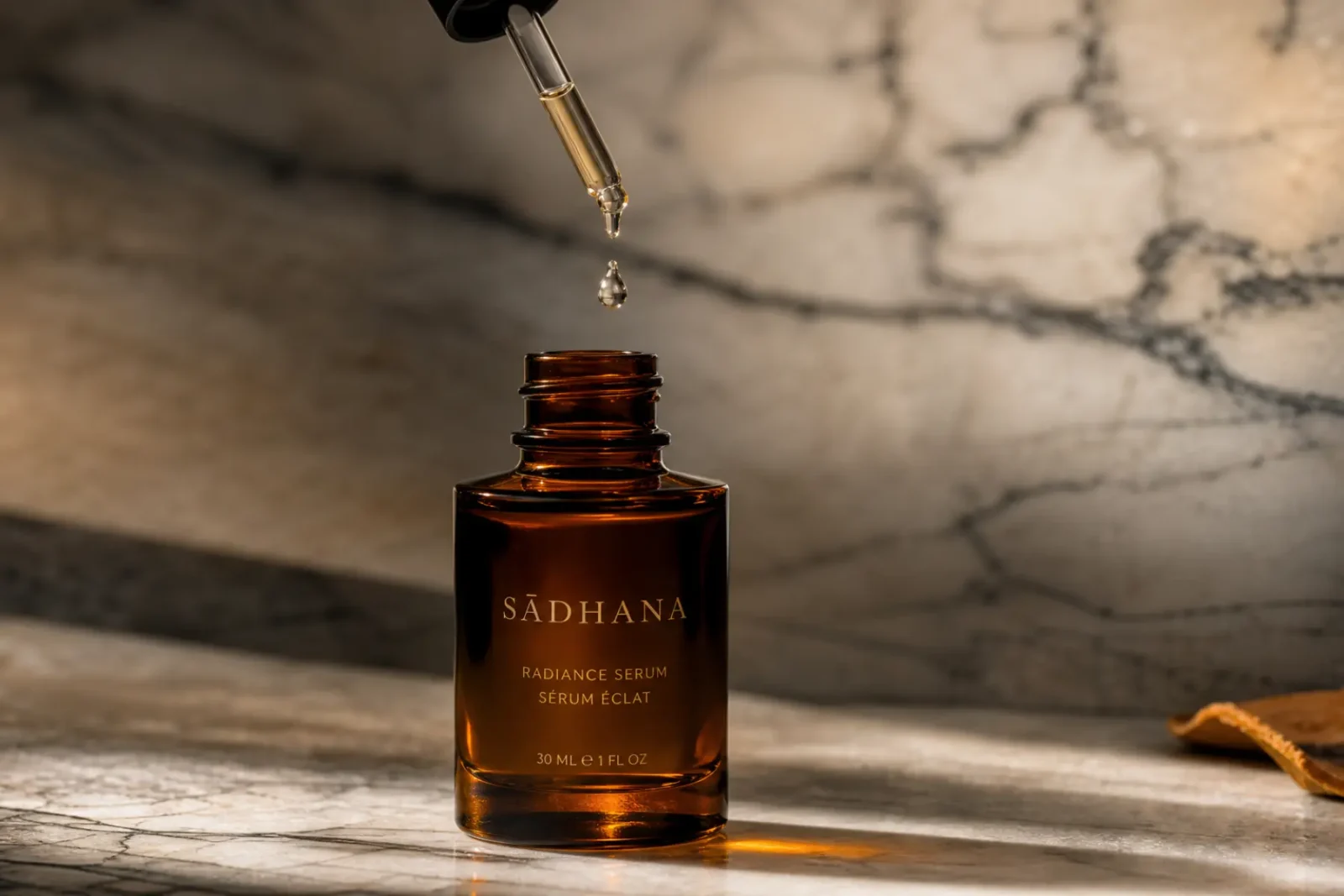 Flacon de sérum visage au curcuma en verre ambré sur marbre blanc, goutte de sérum translucide