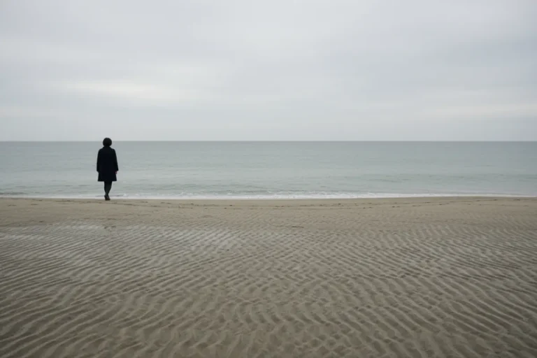 Plage déserte au Japon en automne avec une femme seule qui marche au loin face à la mer