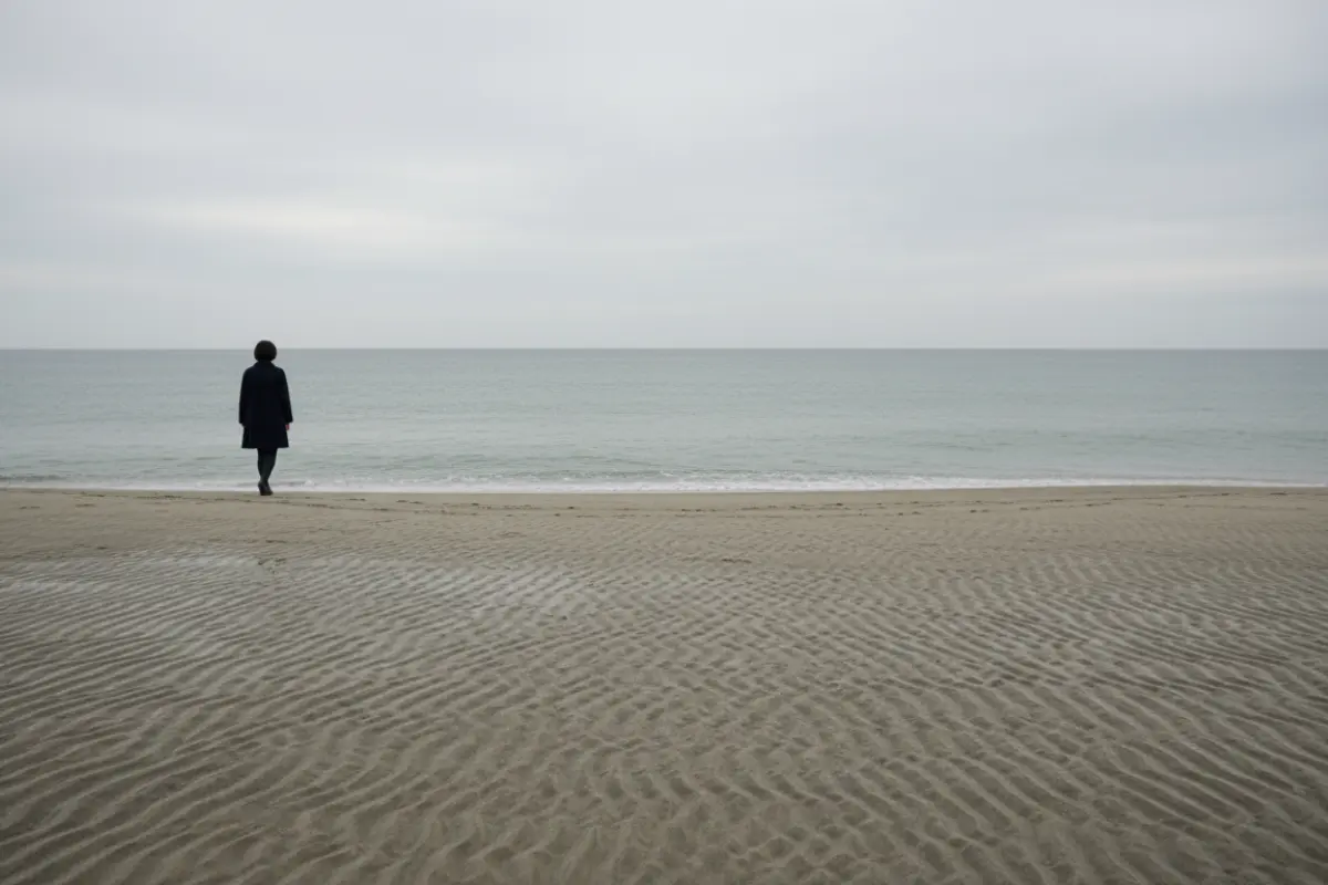 Plage déserte au Japon en automne avec une femme seule qui marche au loin face à la mer