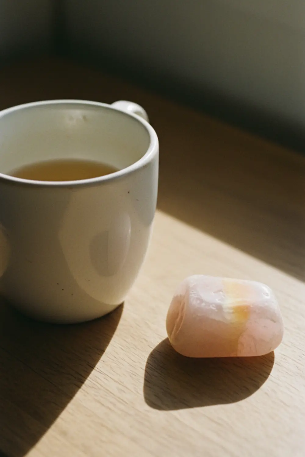 Quartz rose posé près d'une tasse de thé, rituel calme de lithothérapie
