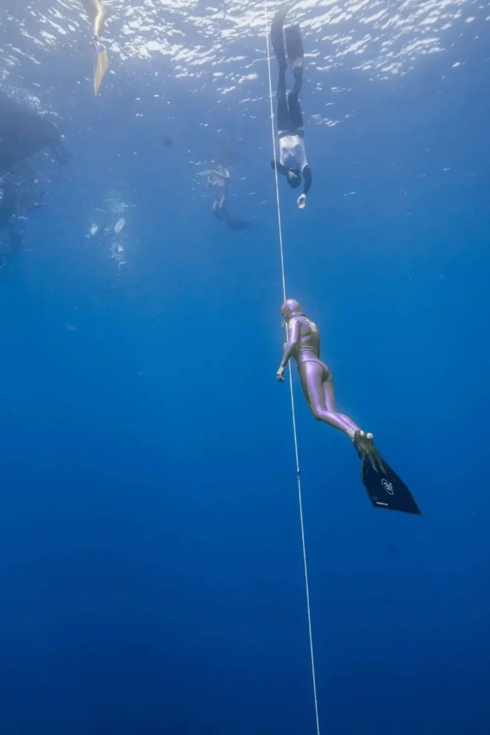 Apnéiste en combinaison métallisée descendant le long d'un câble de guidage sous l'eau.