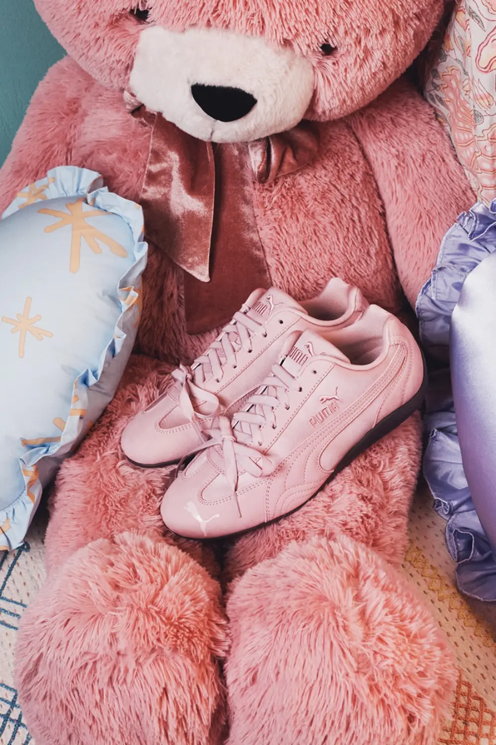 La Puma Speedcat Étoile : la sneaker fine qui fait danser le dressing 4 Baskets Puma Speedcat rose poudré posées sur un grand ours en peluche rose pastel.