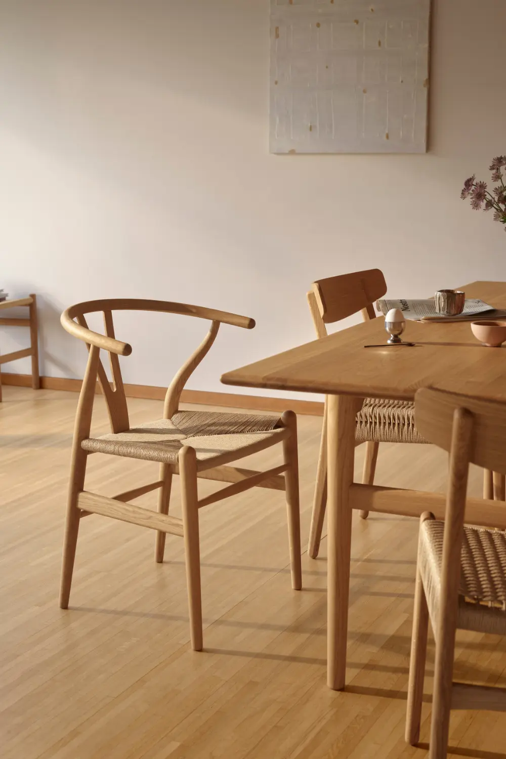 Chaise Wishbone CH24 en bois naturel et assise tressée près d'une table à manger.