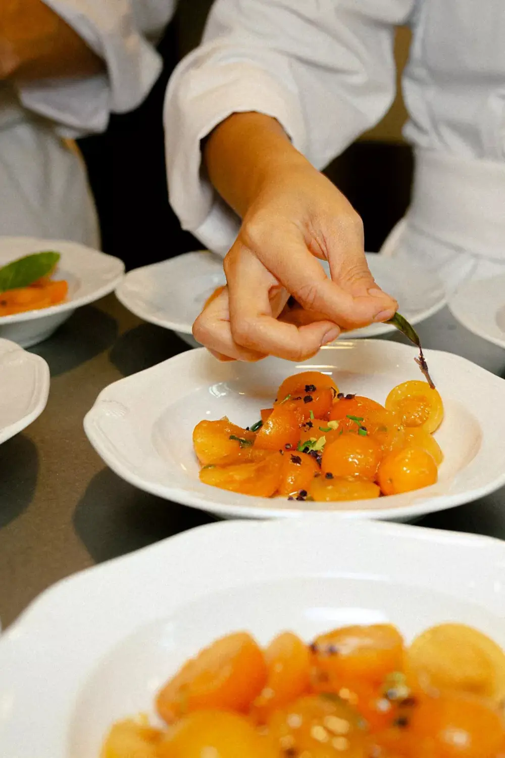 Chef préparant un plat de tomates cerises marinées or au restaurant Mosaic.