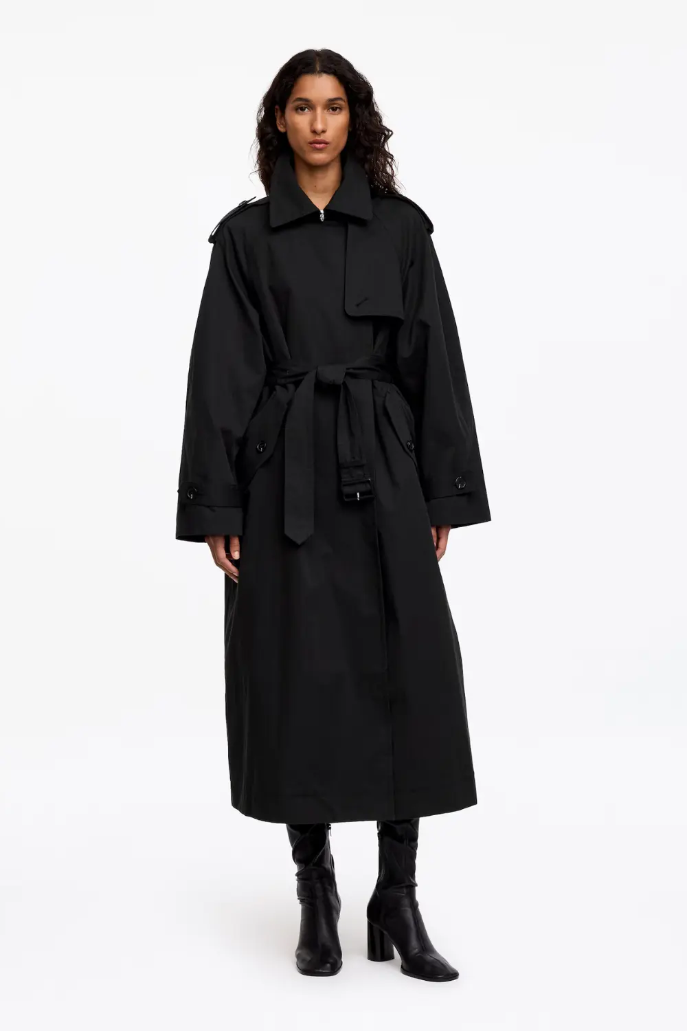 Rentrée 2026 : les 5 pièces d'allure qui font pivoter tout le dressing 5 Femme portant un trench-coat noir oversize ceinturé de la marque Arket.